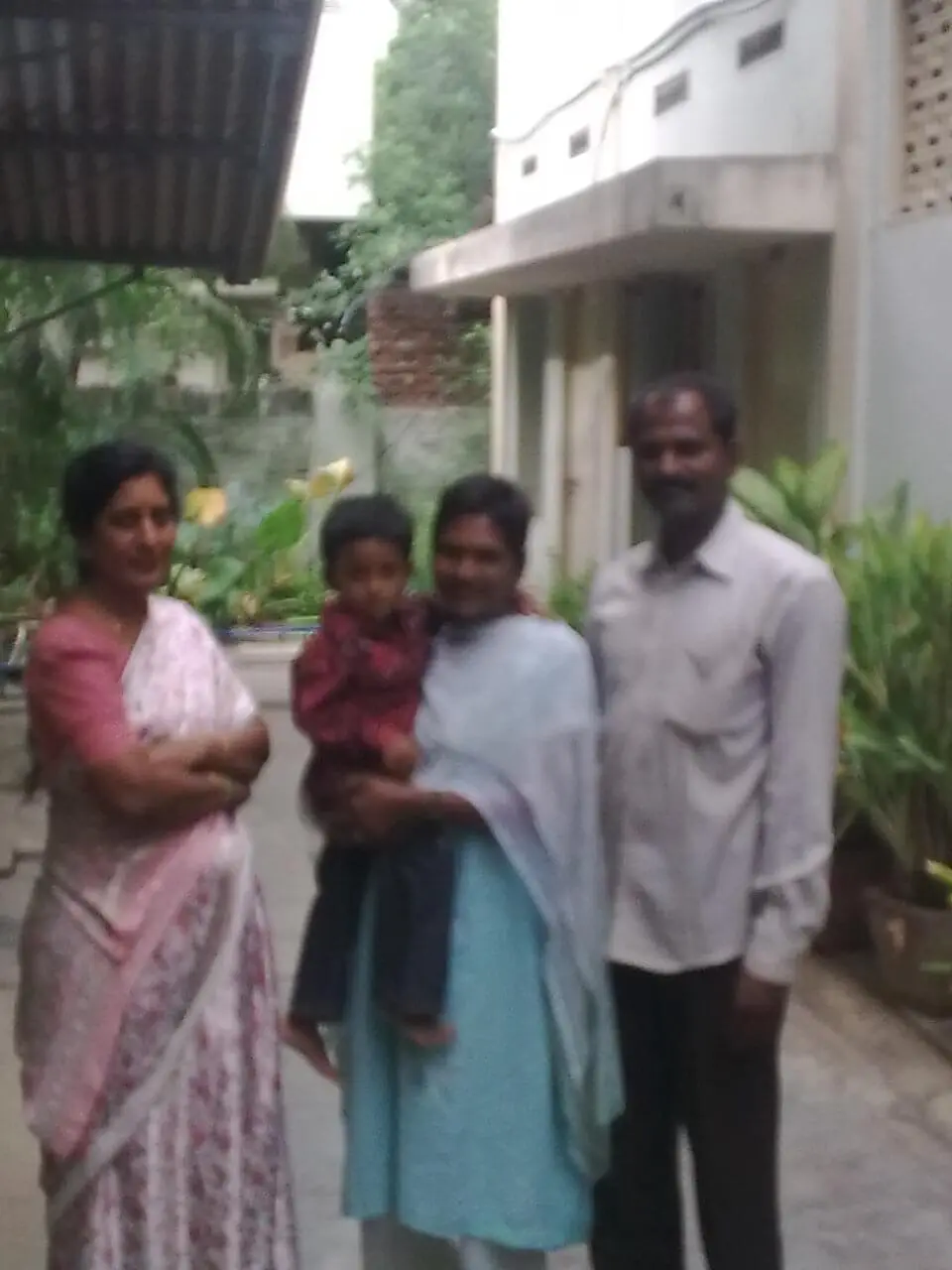 Dr. Rama Devi Kolli standing with a happy couple and their two year old son. Photo from 2005.