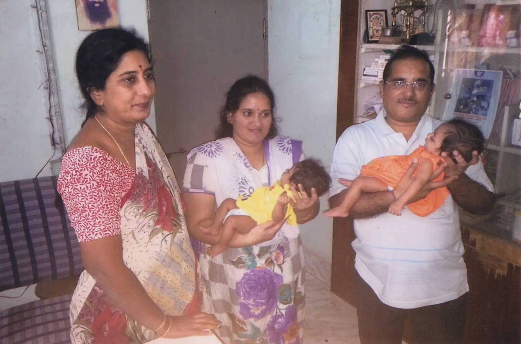 Dr. Rama devi Kolli standing beside the father and mother of IVF twins, each holding one infant in their arms. Photo from 2007.