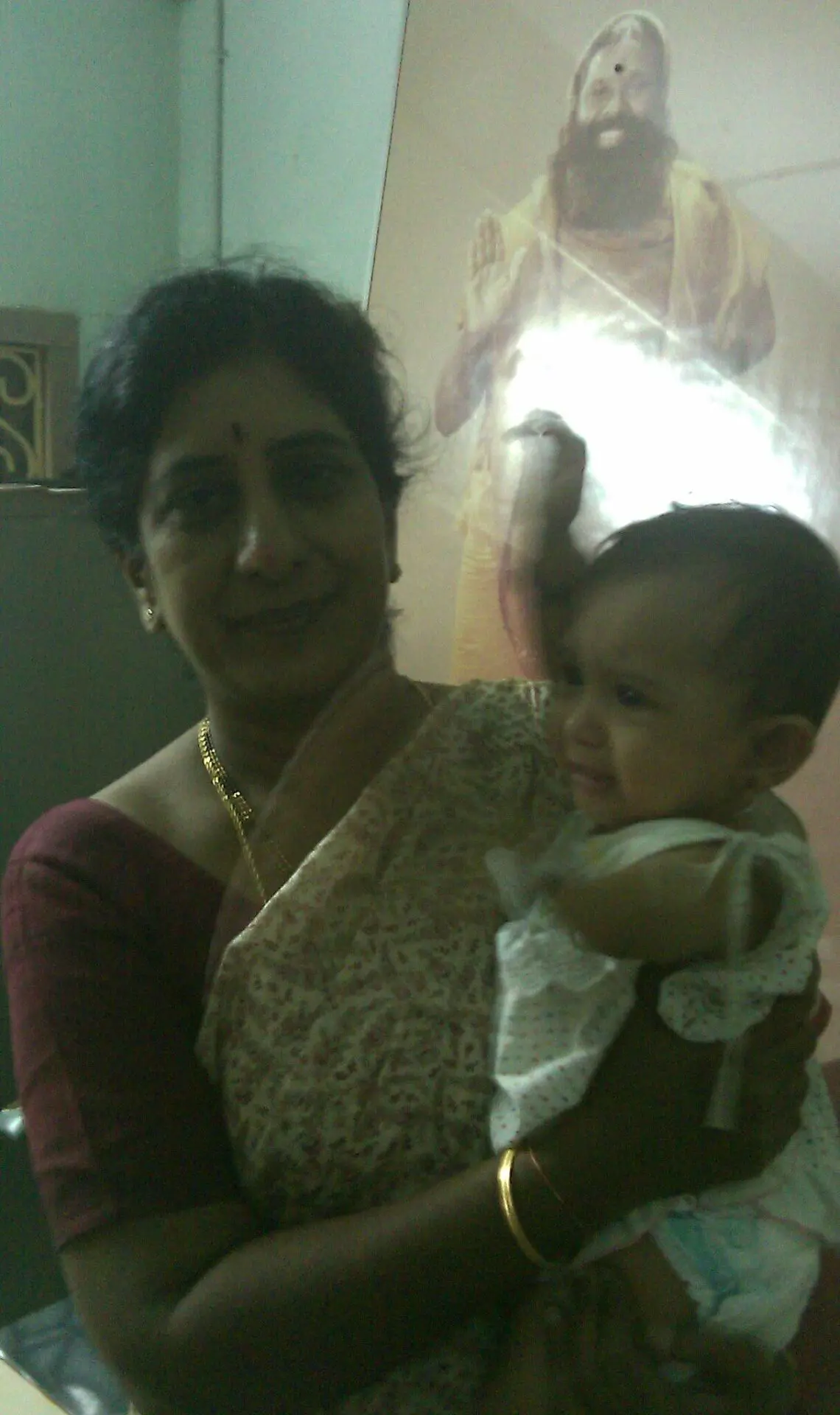 Dr. Rama Devi Kolli standing and holding a baby in her arms. The baby was born to an NRI couple from UK, after IVF treatment at Karthika Datta's IVF clinic in 2010.