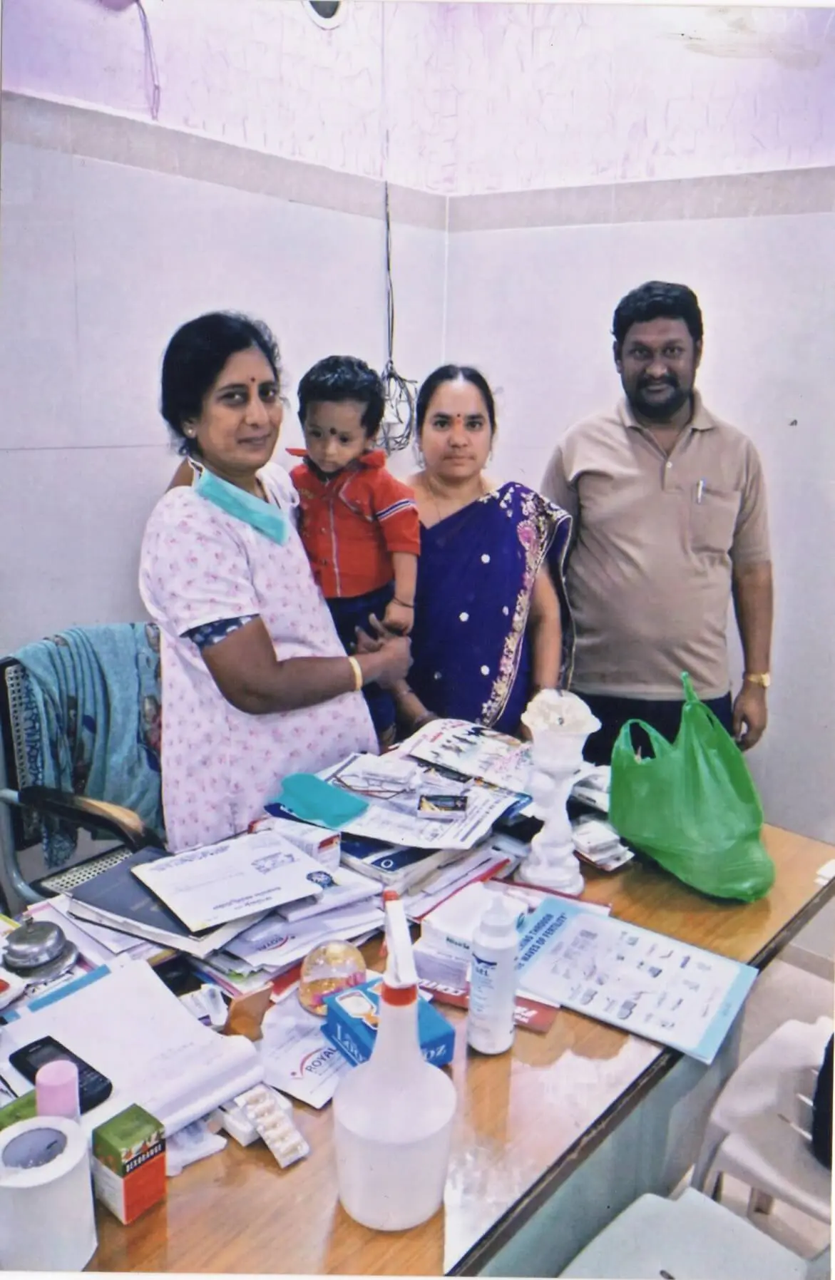 Left to Right, all standing, Dr. Rama Devi Kolli holding a young boy; the mother; the father, both smiling. This boy was born through ICSI at Karthika Datta's IVF.