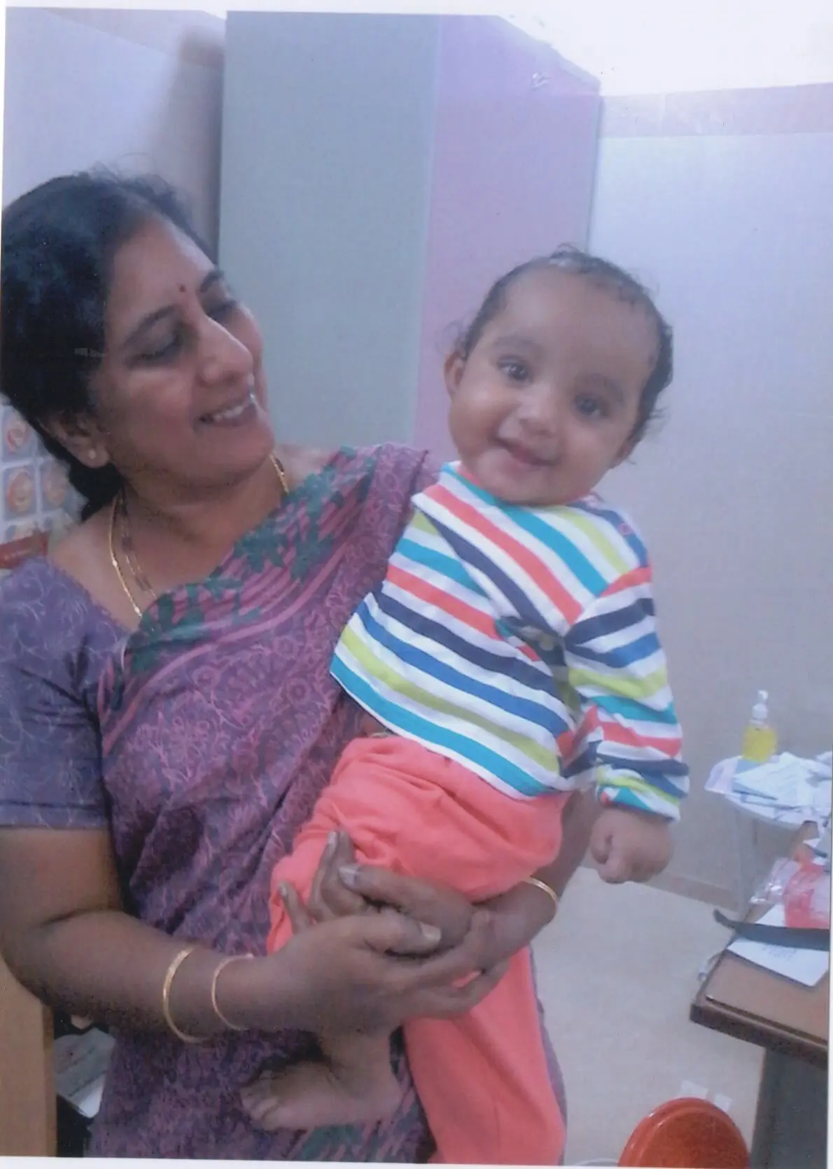 A smiling Dr. Rama Devi Kolli, standing holding a delighted looking 1 year old boy. This boy was born after IVF treatment at our center. Photo from 2016.