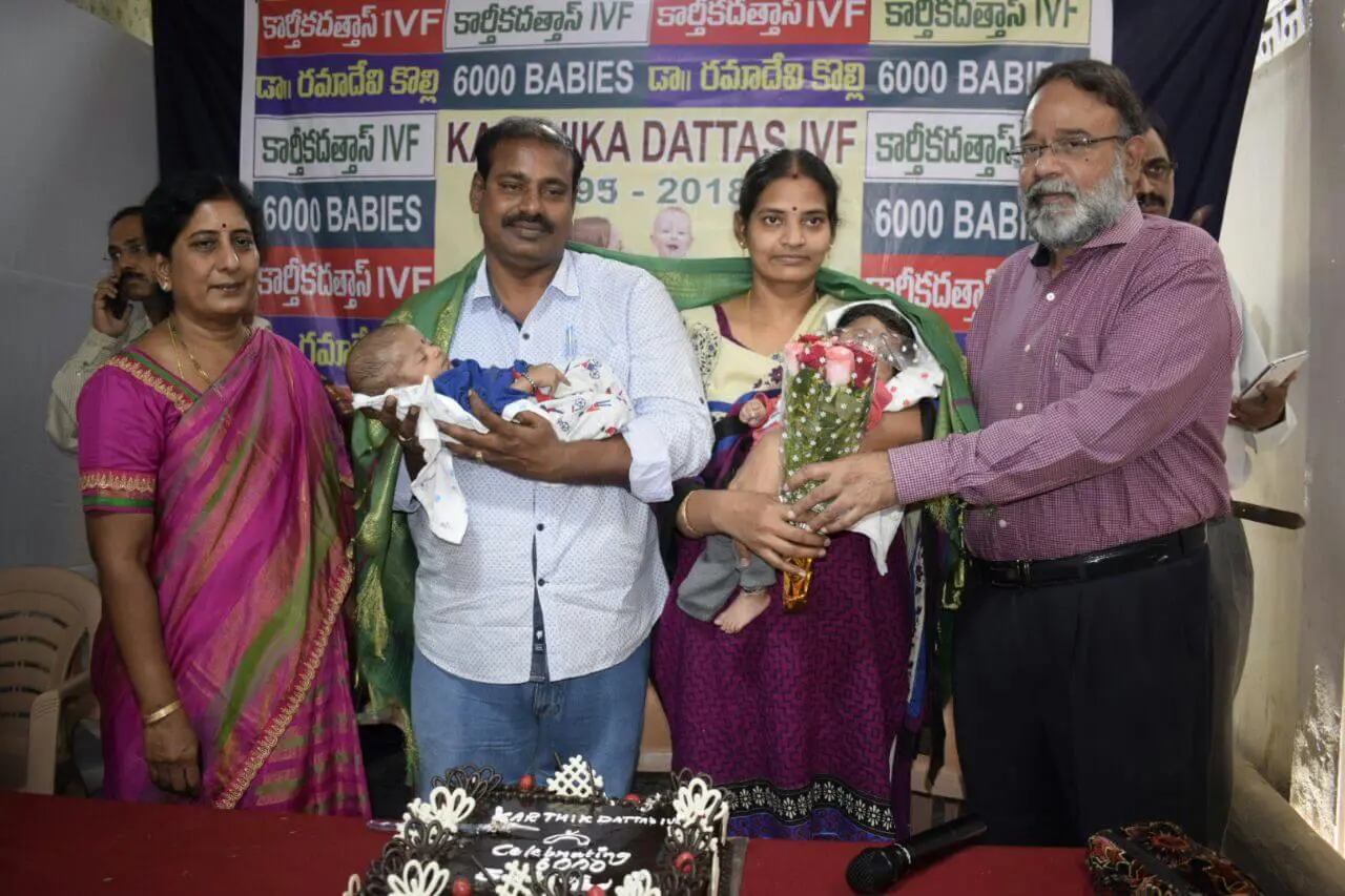 L to R, all standing, Dr. Rama devi Kolli; parents of the 6000th baby to be born through infertility treatment at our clinic, each holding one of their twins; Dr. K E V Rajendra Prasad. The doctors are seen congratulating and felicitating the couple.
